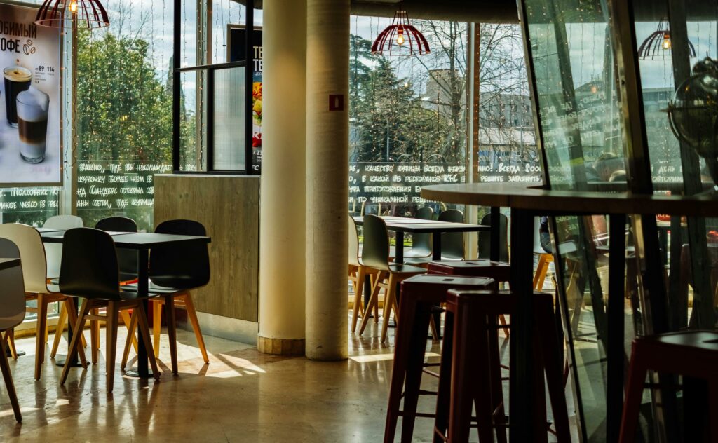 Sunlit modern cafe interior with stylish furniture and decor, offering a cozy ambiance for dining or coffee.
